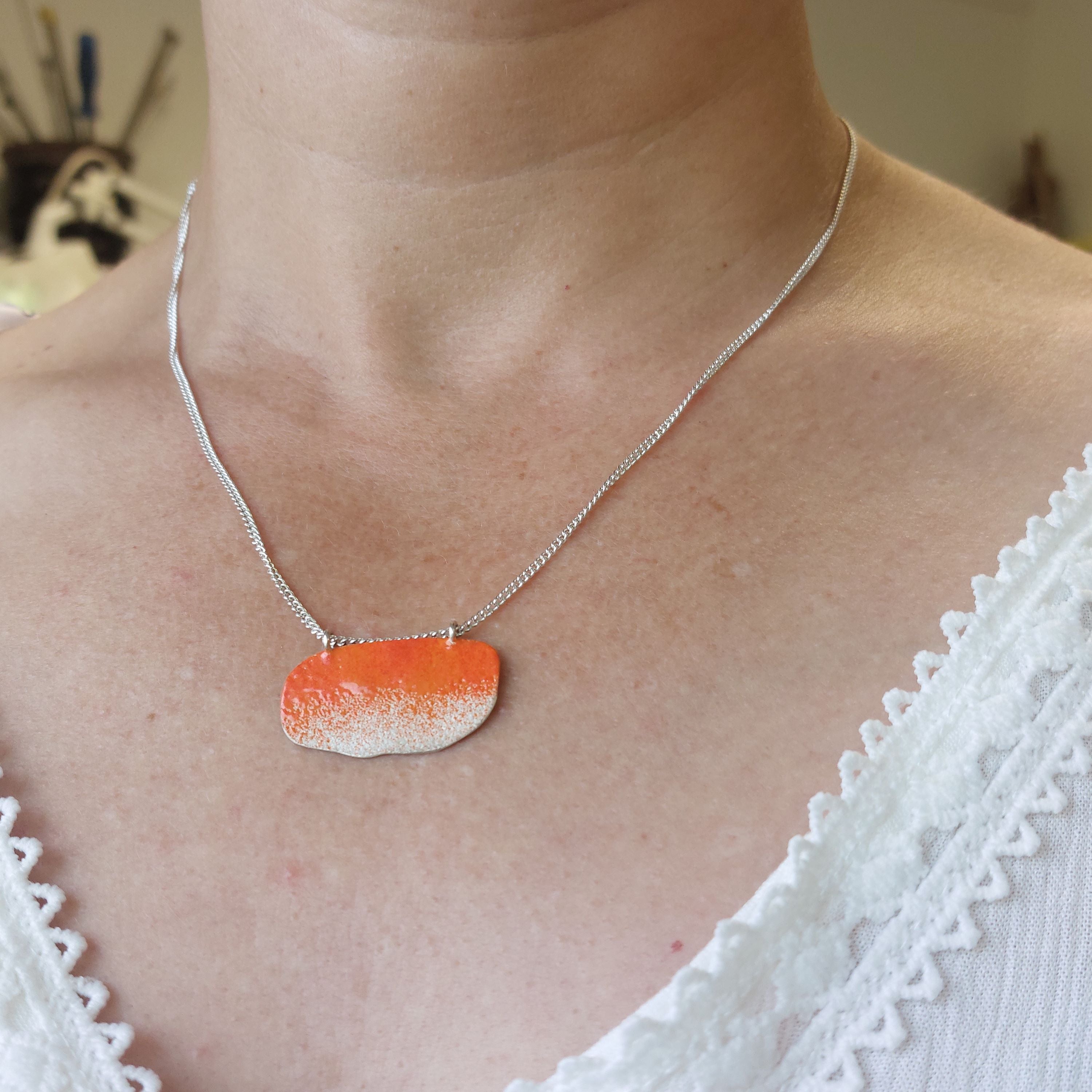 Organic shape sterling silver necklace with bright orange powder coated detail.