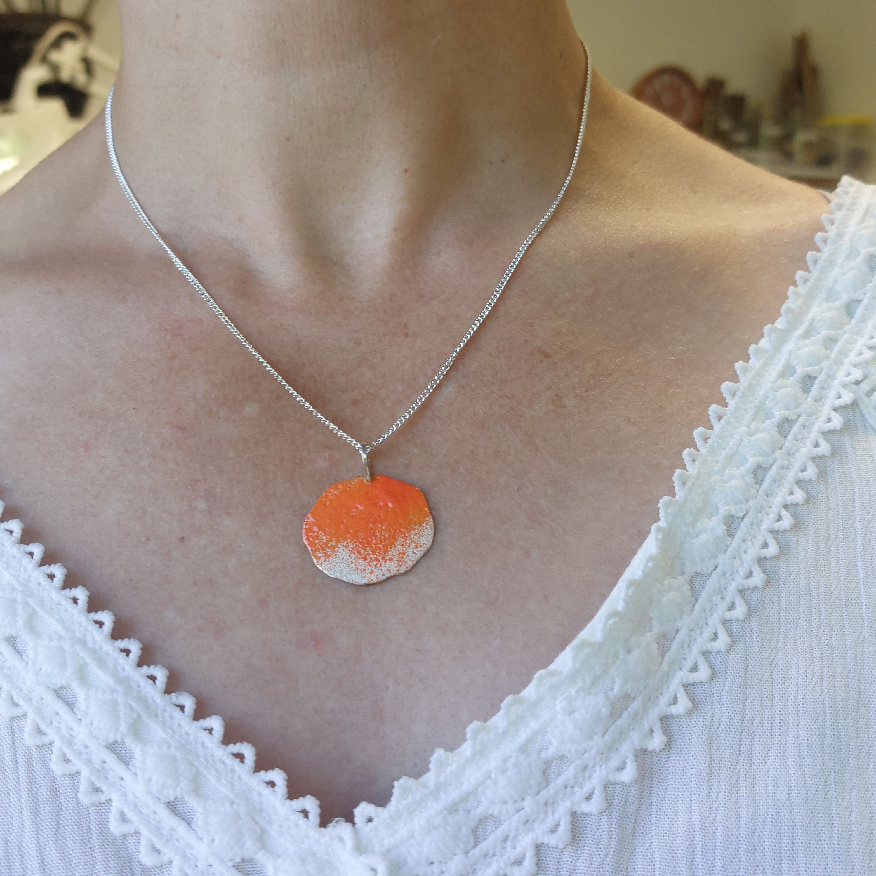 Sterling silver organic shape necklace with orange bright powder coat on a models neck