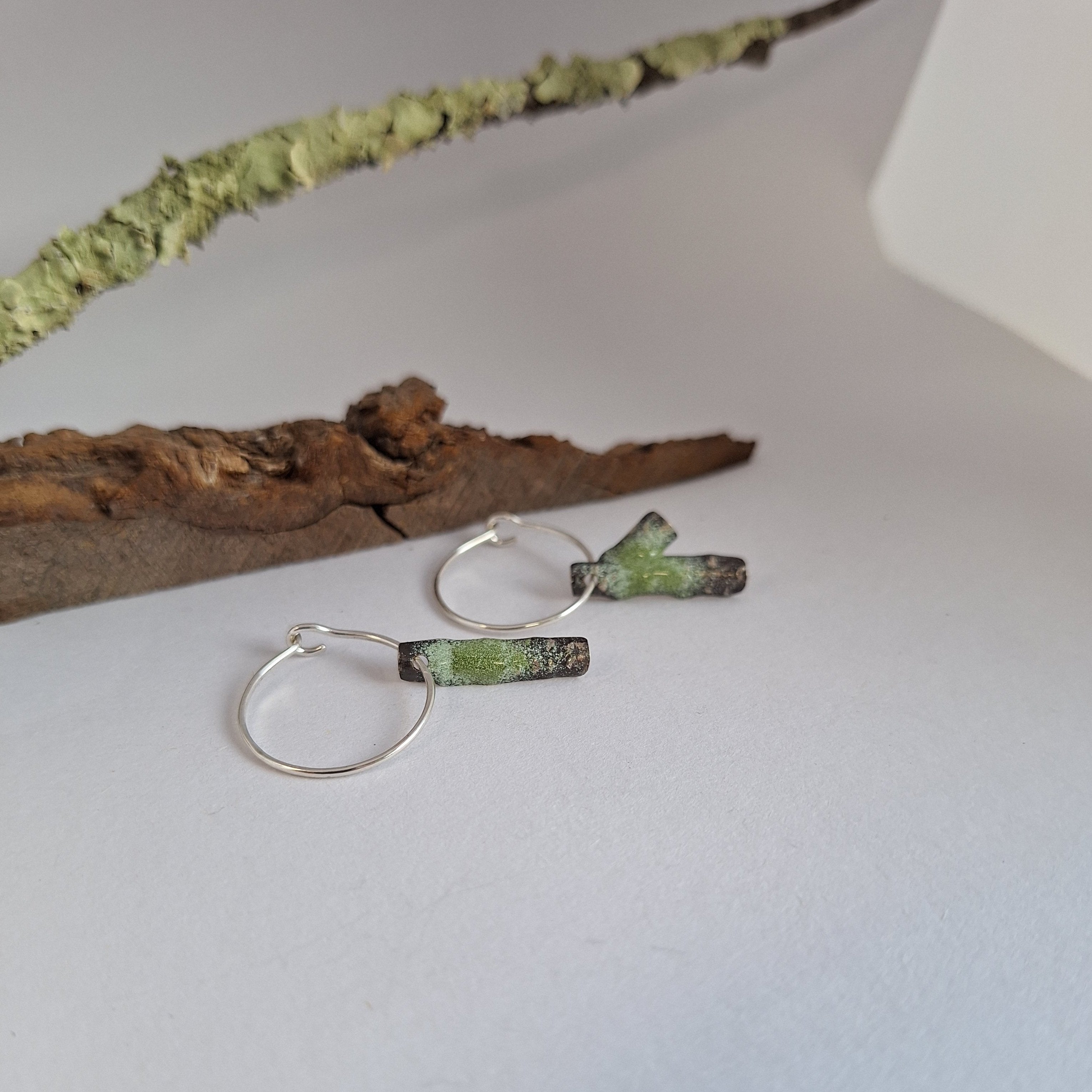 Oxidised Sterling silver branch hoop earrings with green powder coat on a white surface