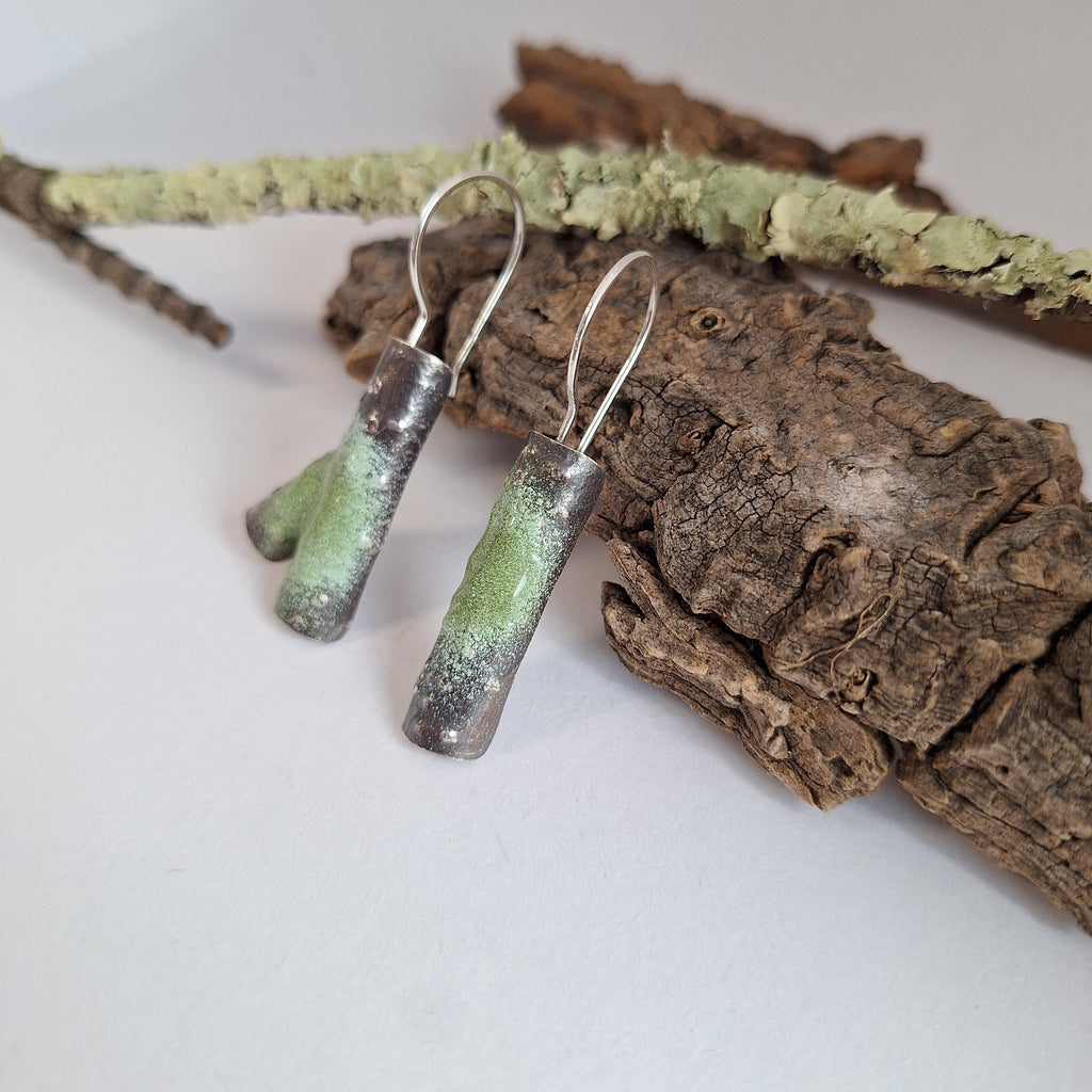 Sterling silver twig earring with powder coated lichen resting on tree bark