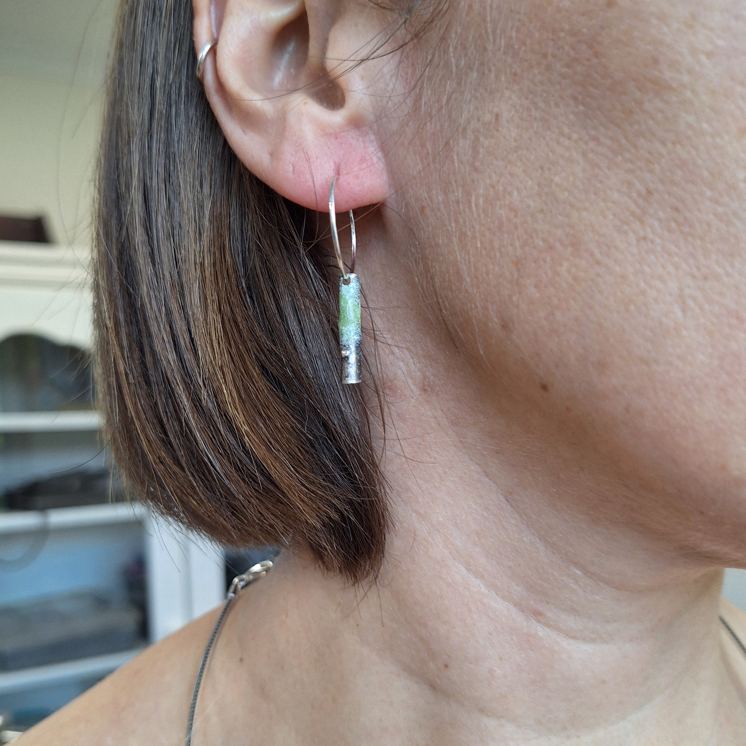 Sterling silver twig earring with powder coated lichen on ear