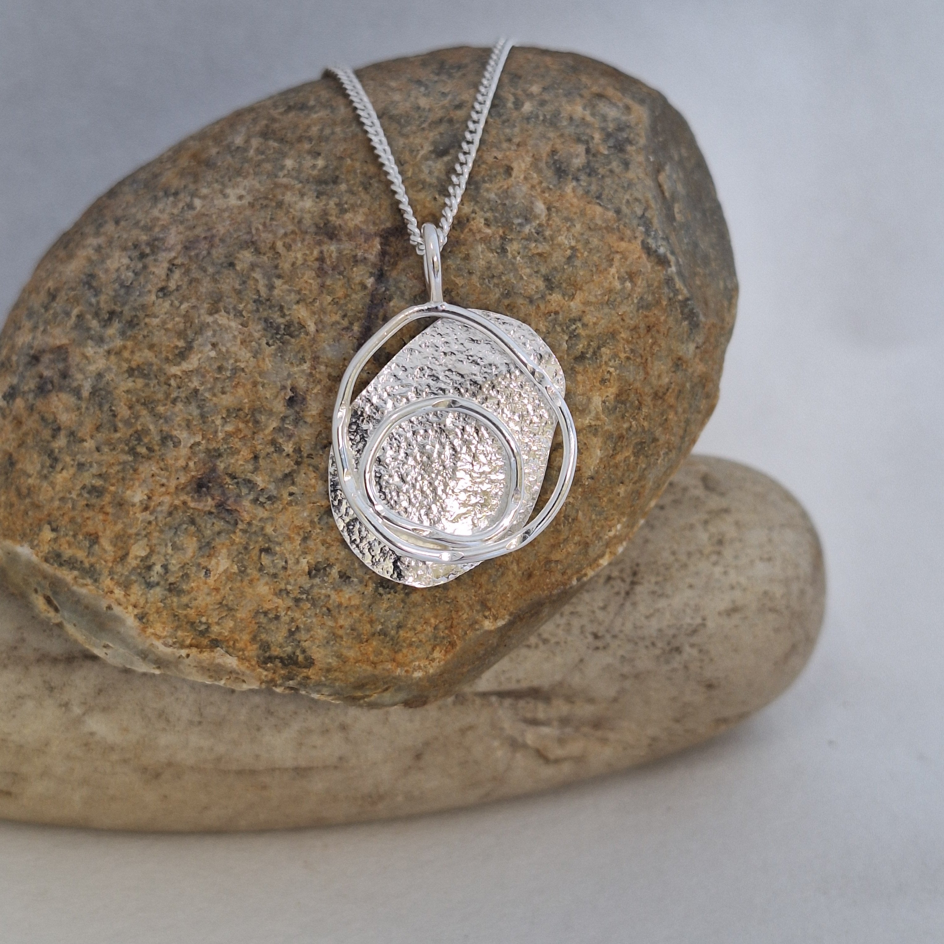 Sterling Silver beach boulder inspired necklace on a rock