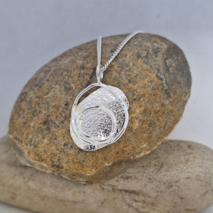 Sterling Silver beach boulder inspired necklace on a rock