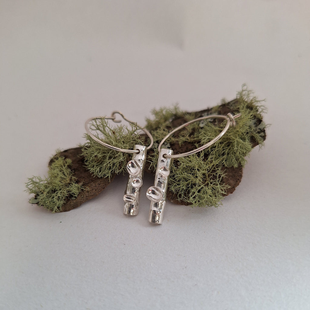 twig earrings with lichen structures in sterling silver on lichen covered bARK