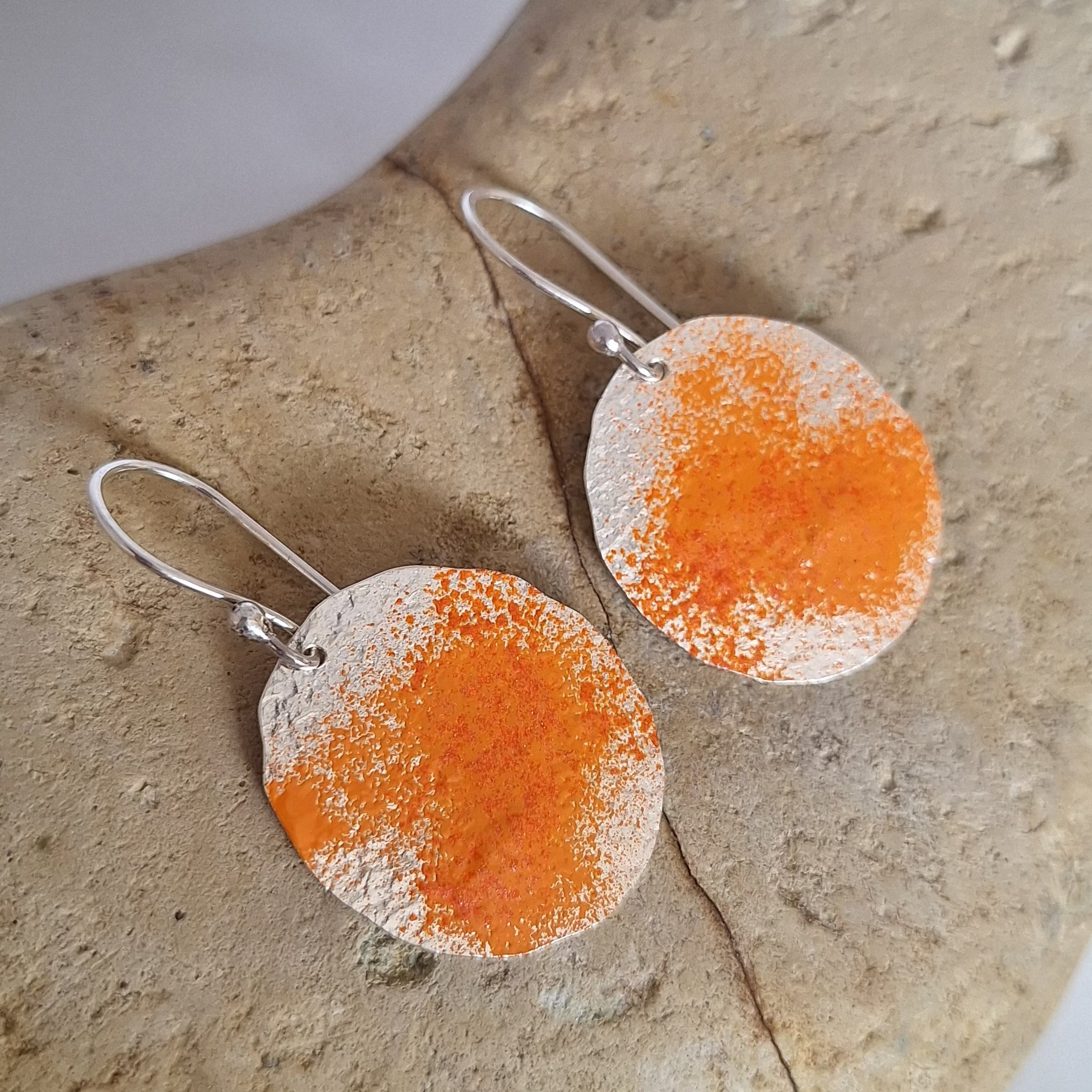 Sterling silver dangle earring on rock with orange powder coat to represent lichens on boulders of tassie east coast.