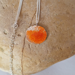 Load image into Gallery viewer, Orange and sterling silver necklace on rcok
