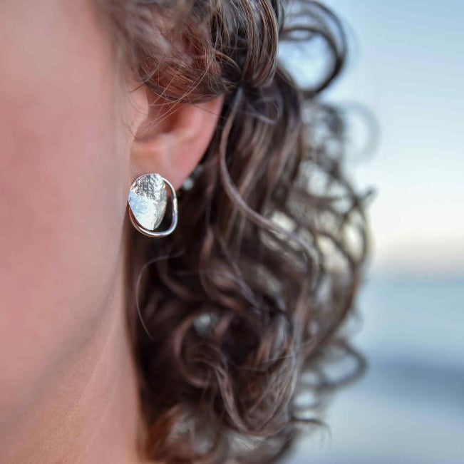 Sterling silver Tasmanian each boulder inspired stud earrings on a model on the beach.