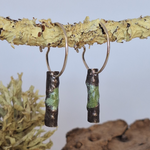 Load image into Gallery viewer, Sterling silver hoop earrings with powder coat accents hanging on lichen covered twig
