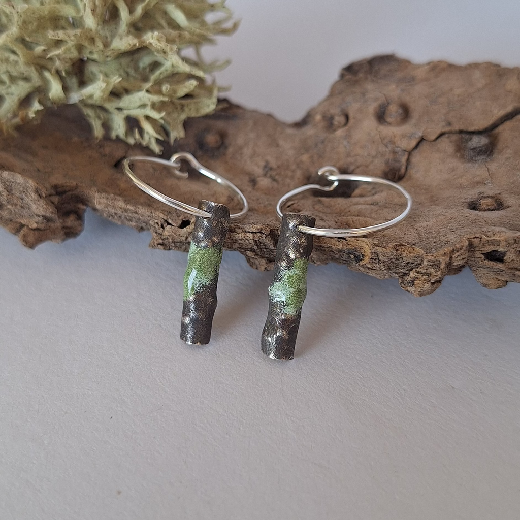 Sterling silver hoop earrings with powder coated accents on a piece of tree bark.