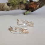 Load image into Gallery viewer, Sterling Silver Tasmania Hoop earrings on a white surface with a lichen branch in the background.
