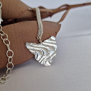 Tasmania necklace in Sterling silver resting on a dried leaf.