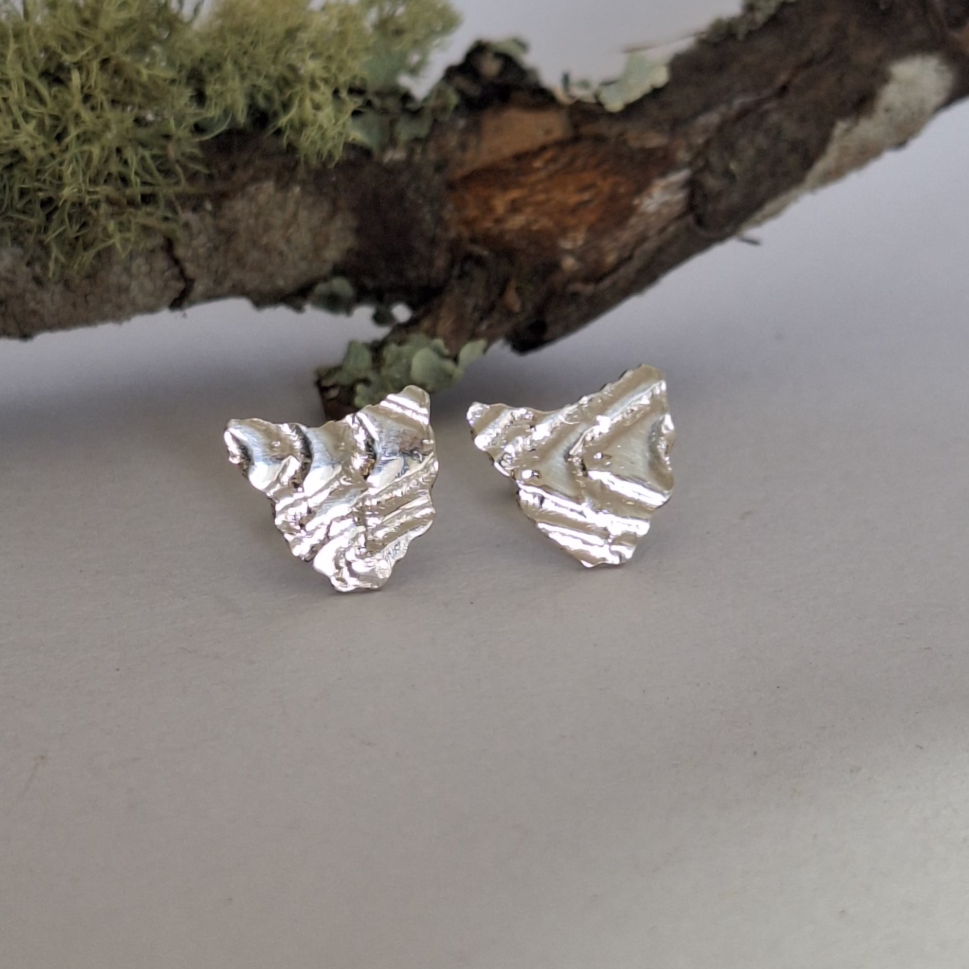 Sterling silver stud earrings in the shape of Tasmania with contour lines. Polished finish