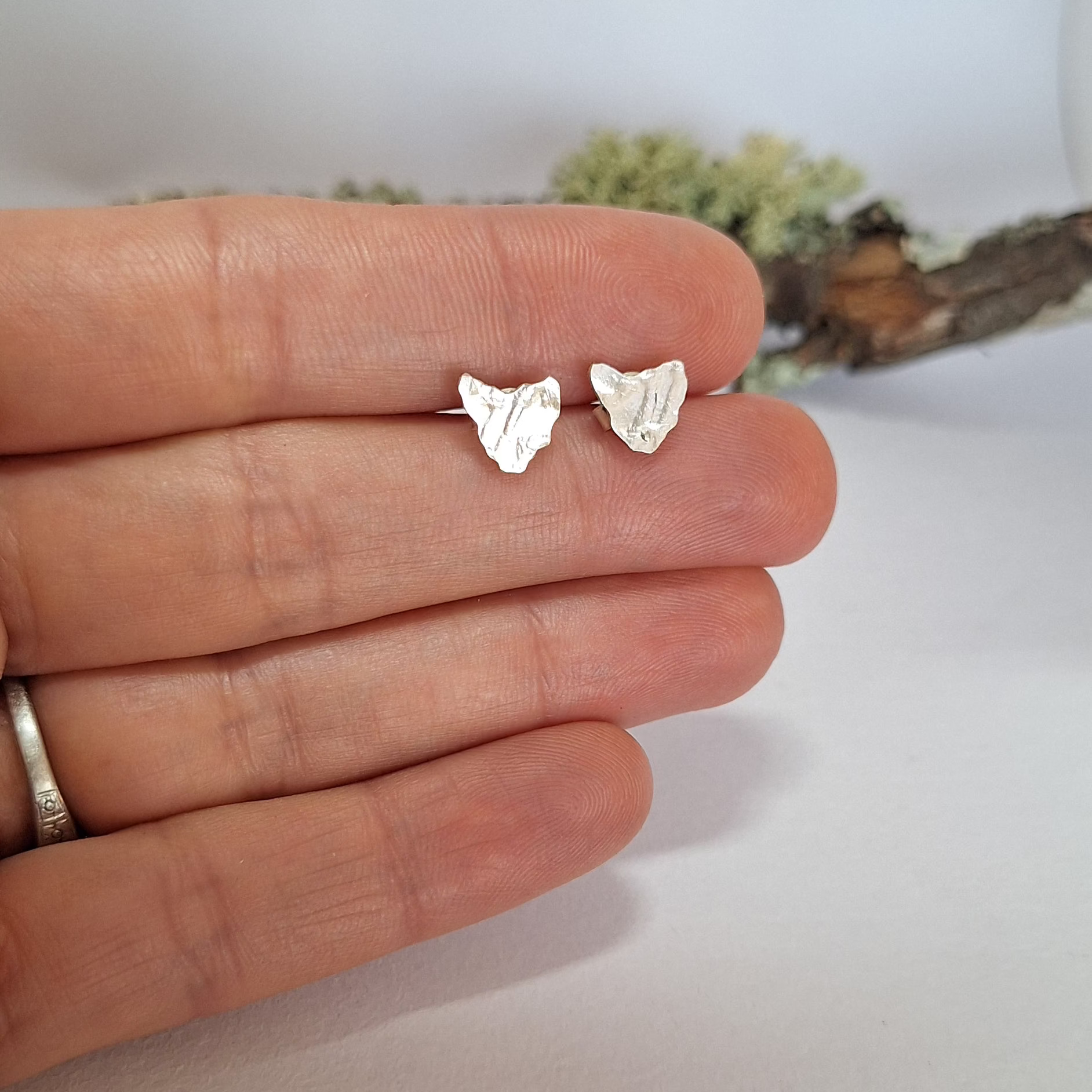 Dainty Sterling silver studs in the shape on Tasmania pictured on hand.